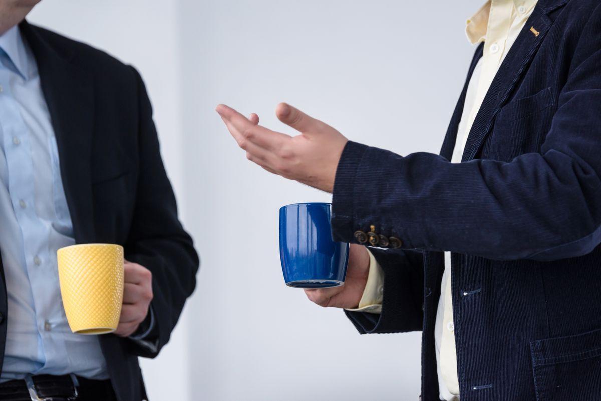 Two office workers have a discussion at the coffee-break time