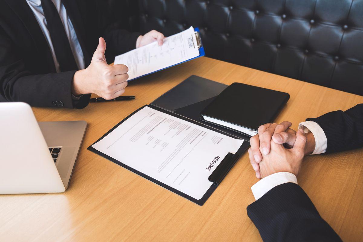 Employer or recruiter holding reading a resume during about his profile of candidate, employer in suit is conducting a job interview, manager resource employment and recruitment concept.